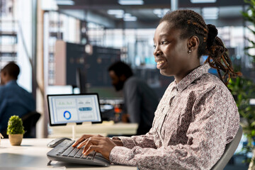 Fototapeta premium Black business manager engaged in budget analysis and strategy development at workstation, supporting objectives for company growth and employee collaboration. Strategizing business goals.