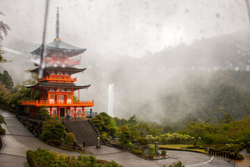 Nachisan Seiganto-ji Temple pagoda with Nachi Waterfall behind in the rain from underneath an umbrella, April, Japan