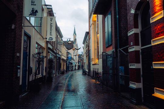A narrow, picturesque street in Enschede, Netherlands, with charming brick buildings, wet pavement, and a cozy, atmospheric vibe. Perfect for urban exploration. Enschede, Netherlands. January 6 2025