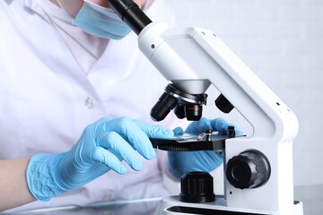 Laboratory testing. Scientist examining sample on slide under microscope indoors, closeup