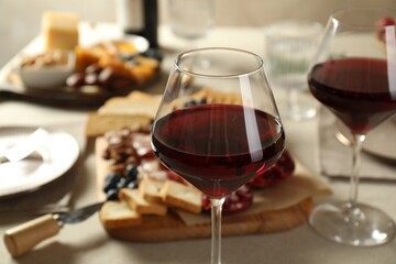 Red wine and different snacks served on table, closeup