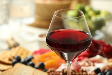 Red wine and different snacks served on table, closeup. Space for text