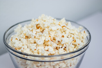 Tasty popcorn in a glass bowl on white table background 