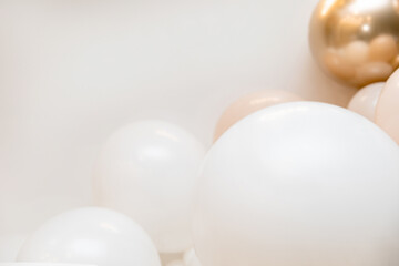 Stylish balloon composition with white, blush pink and metallic gold balloons arranged at the bottom of a light grey backdrop. Clean, minimalist corner setup perfect for celebrations.