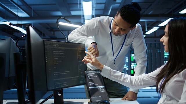 Team of admins in data center ensuring system can handle networking tasks. Teamworking colleagues in server room tracking network traffic with PC, making improvements, camera B