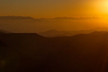 Russia. North Caucasus, Karachay-Cherkessia. Evening view of the mountain peaks of the Elbrus region against the background of the crimson setting sun.