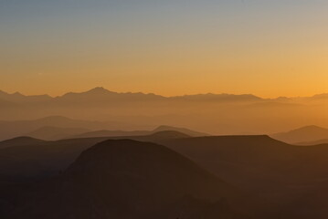 Russia. North Caucasus, Karachay-Cherkessia. Evening view of the mountain peaks of the Elbrus region against the background of the crimson setting sun.
