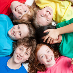 Early Teens: Laughing Friends. High angle view of a circle of early teenage friends looking up with cheeky smiles for the camera.