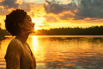 Fototapeta premium Woman standing near a lake at sunset enjoying the serene beauty of nature