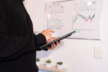 business management concepts. businessman draws graphs on whiteboard while reviewing data on digital tablet
