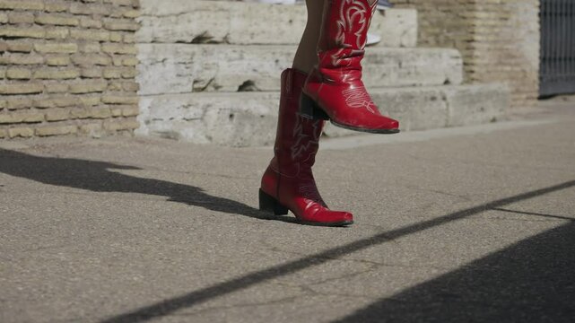 Tourist person in red cowboy boots dancing outdoors visiting ancient Colosseum in Rome, Italy, slow motion