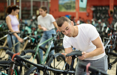 Young man buyer chooses bicycle in sports store