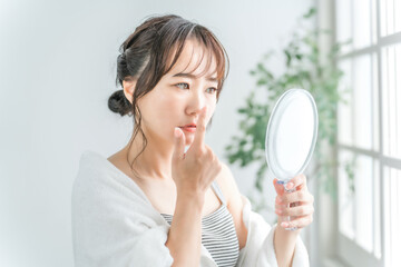 鏡を見て小鼻の毛穴を見る日本人女性
