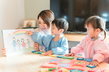 Fototapeta premium 保育園・幼稚園・託児所・保育所で園児に紙芝居・絵本を読み聞かせする女性保育士・保母さん・シッター保育 