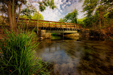 Fototapeta premium Letort Spring Run flowing under a foot bridge as it winds through a quiet and peaceful meadow.