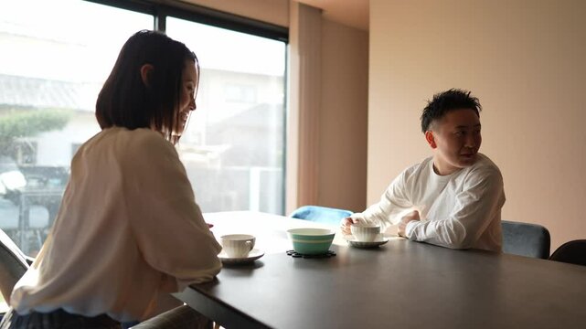 A Japanese couple, a woman in her 30s and a man in his 20s, are enjoying afternoon tea time at home. Slow motion video.