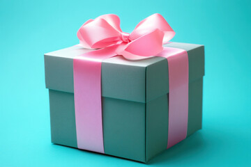 Obraz premium Pink and gray gift box with a pink bow on a wooden table, soft light highlighting the delicate color scheme and elegant presentation.
