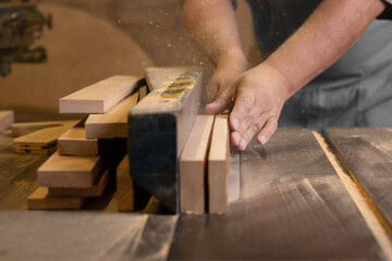 A male carpenter cutting wood with a circular saw in a carpentry sho