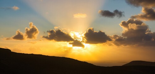 A stunning sunset lights up the sky with golden rays and fluffy clouds, creating a picturesque scene