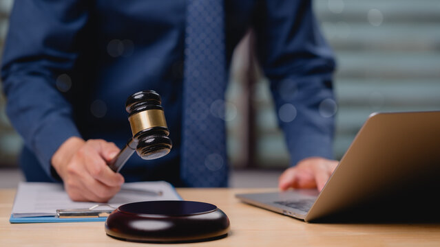 Professional figure prepares to issue ruling with gavel in hand, symbolizing intersection of traditional law practices and modern technology in todays legal environment