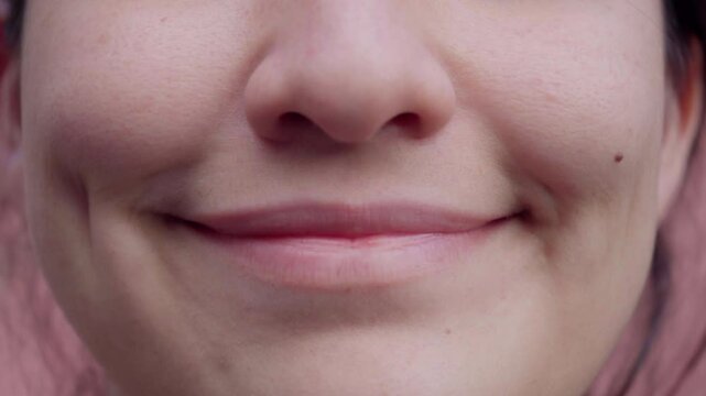 Close-up of a smiling person showcasing a warm expression and dimples in a relaxed outdoor setting. A person smiles warmly, revealing dimples and a cheerful demeanor. 