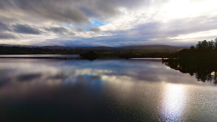 Lough Eske in Donegal Ireland - A tranquil view of a lake reflecting the cloudy sky at dusk,...