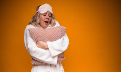 A woman in a white robe and pink sleep mask, yawning while hugging a soft pink pillow. The vibrant...