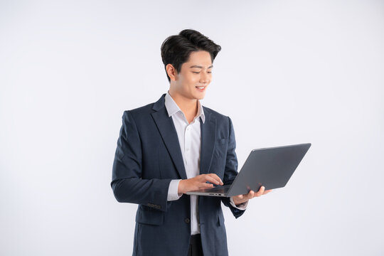 Portrait of young Asian business man using laptop and posing on white background