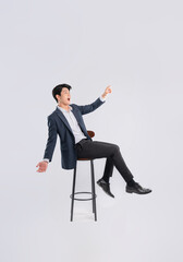 Full body image of young Asian business man sitting in chair on white background