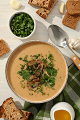 A bowl of cream of mushroom soup with parsley and croutons