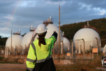 A female engineer with a green safety jacket holding walkies talkies checking on the site of the...