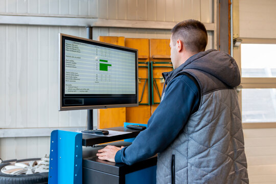 Young repairman  technician mechanic uses pc computer with car diagnostic software. Mechanic man checking car in workshop at auto car repair service center. Automotive Electronic Diagnostic.