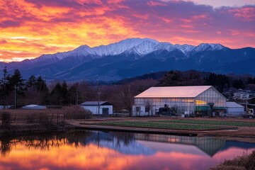 Fototapeta premium Serene Sunset Over Mountain Landscape with Greenhouse and Reflective Water, Capturing Nature's Beauty and Tranquility in Rural Setting