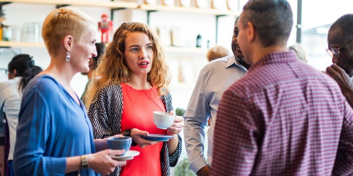 Group of diverse people in casual attire having a coffee break, chatting and enjoying coffee. Social interaction and coffee cups in a relaxed setting. Diverse people talking together.