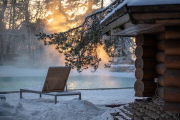 Warm open-air swimming pool with blue water, loungers and wooden Russian bath in sunny cold...