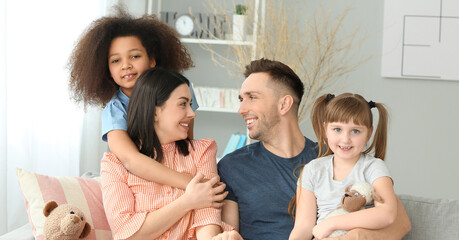Happy couple with little adopted children at home