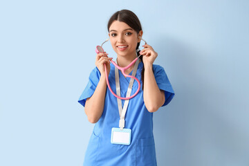 Female medical intern with stethoscope on blue background