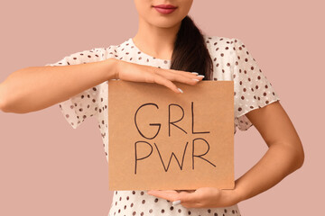 Young pin-up woman holding card with text GIRL POWER on pink background, closeup