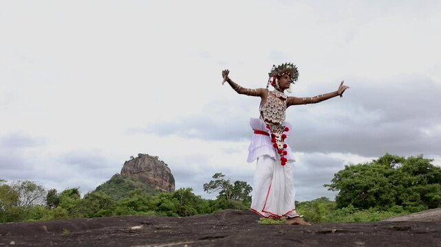A Ves Dancer, also known as a Kandyan Dancer or Up Country Dancer performs at Sigiriya in Sri Lanka. In the background stands Sigiriya Rock.