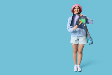Young woman showing map with  magnifying glass on blue background. Travel concept