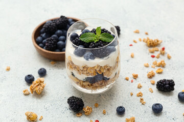Glass of tasty granola with yogurt on light background, closeup