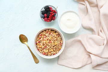 Napkin, bowls with tasty granola, yogurt and berries on pale blue background