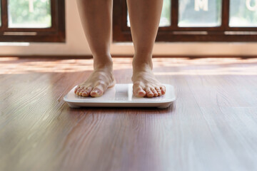 Fat diet and scale feet standing on electronic scales for weight control. Measurement instrument in...