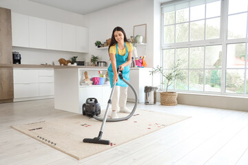 Young woman vacuuming carpet  in kitchen