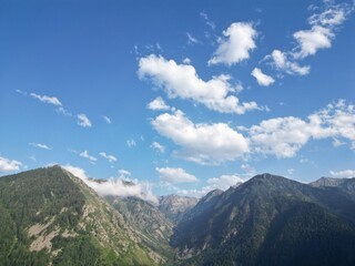 Aerial view of a mountain range with clouds under a blue sky - Vue aérienne d'une chaine de montagne avec des nuages sous un ciel bleu