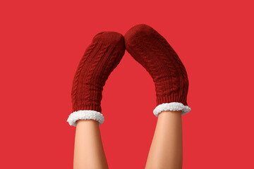 Legs of young woman in warm red socks on color background