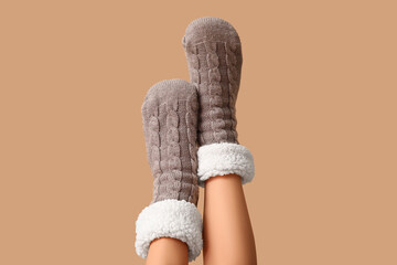 Legs of young woman in warm grey socks on brown background