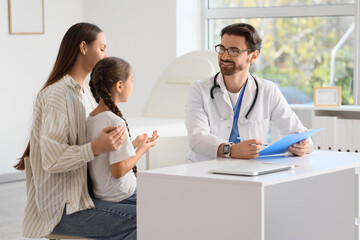Fototapeta premium Male pediatrician working with girl and mother in clinic