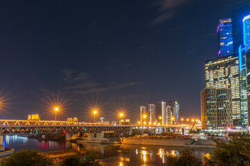 Fototapeta premium The scyscrapers of the Moscow City at night and the Dorogomilovsky bridge with illumination. Translation of text - street names: Krasnopresnenskaya, center, etc.