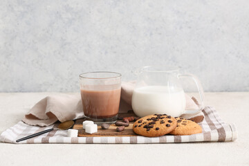 Glass of sweet chocolate milk with cocoa beans and tasty cookies on white background